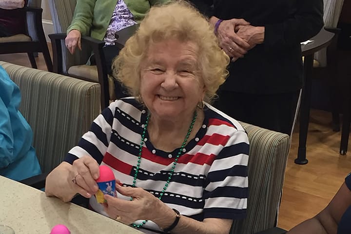Resident smiling at the camera while holding an Easter Egg