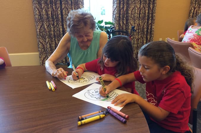 Resident helping children color during their visit